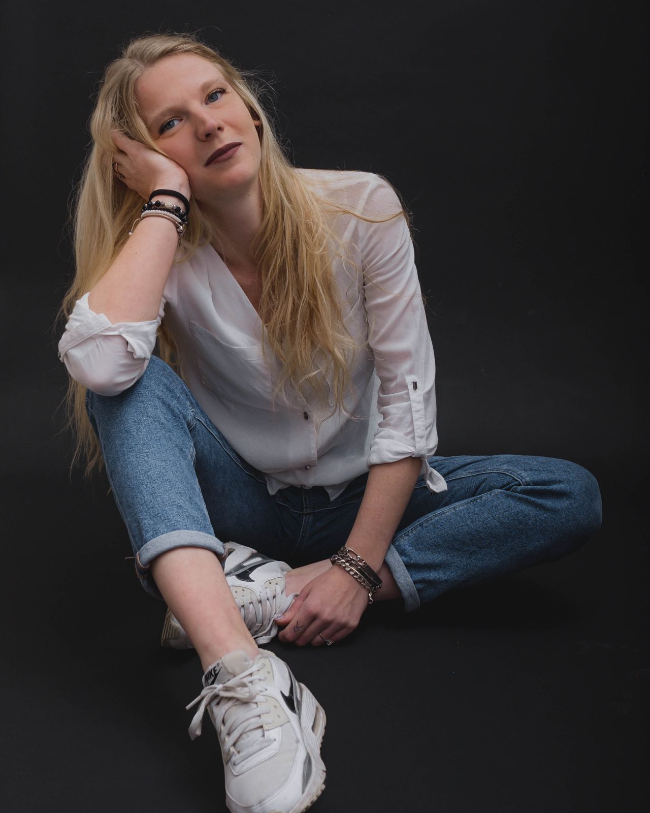 Kassandra seated on the floor in a white shirt and jeans